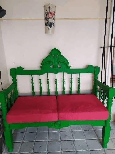 Un banco verde con un cojín rojo en una habitación.
