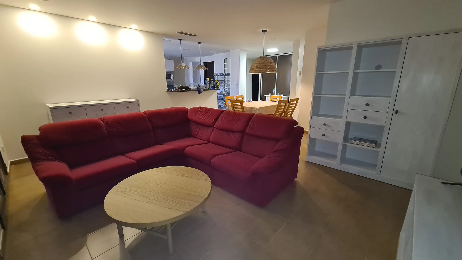 Una sala de estar con un sofá seccional rojo y una mesa de café redonda.