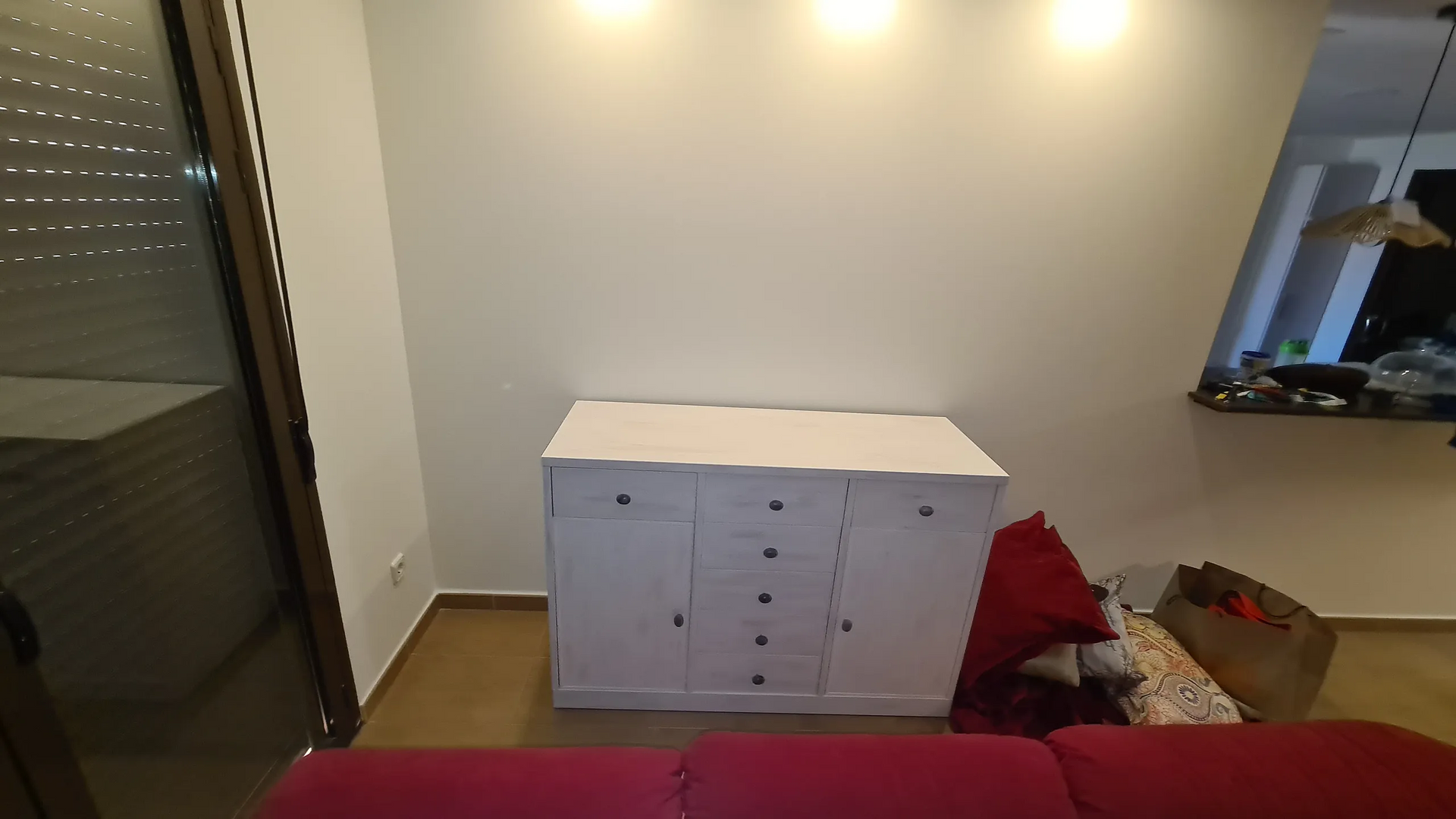 Una sala de estar con un sofá rojo y una cómoda blanca.