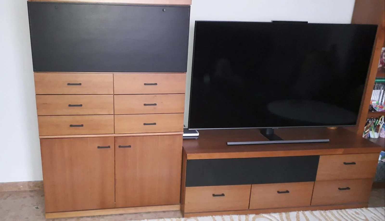 Un televisor de pantalla plana grande se encuentra sobre un centro de entretenimiento de madera.