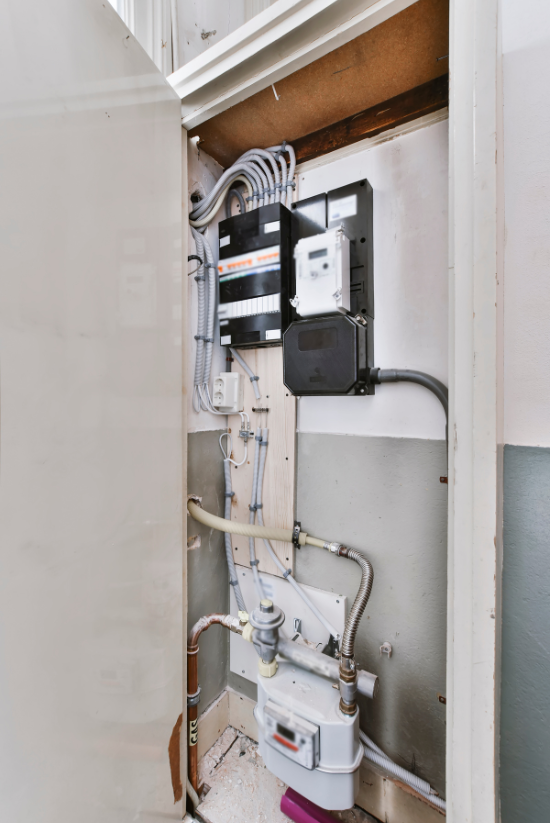 Panneau électrique avec câblage et compteurs montés à l'intérieur d'un placard utilitaire.