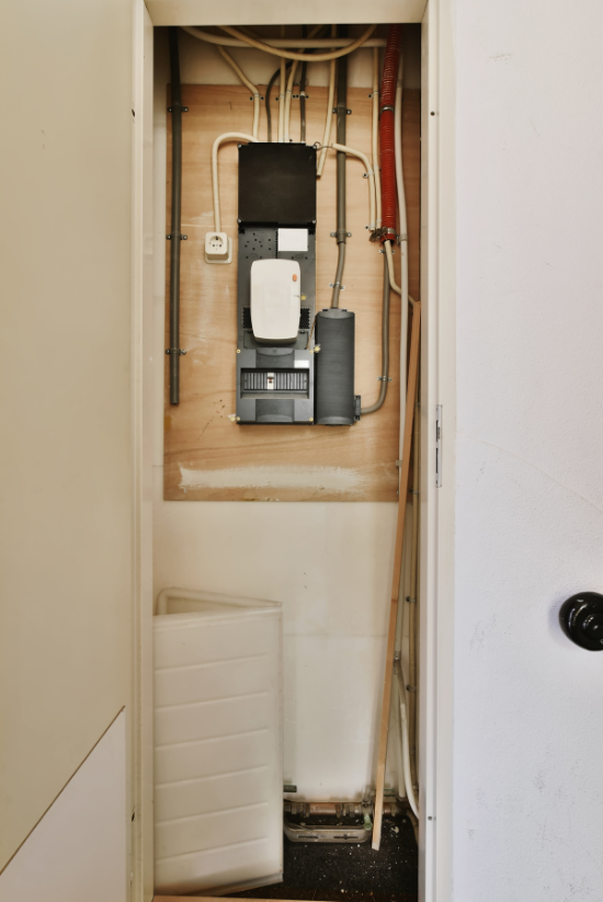 Panneau électrique et câblage dans une petite cavité murale, montrant la distribution électrique et les connexions.