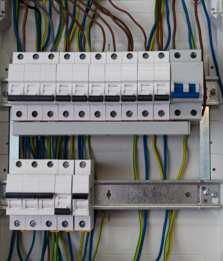 Panneau électrique avec rangées de disjoncteurs blancs et de fils colorés.
