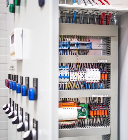 Panneau de commande électrique avec fils de différentes couleurs, interrupteurs et disjoncteurs.