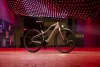 Bicicleta de montaña expuesta en una sala de exposición con iluminación tenue de color rojo y techo resplandeciente.