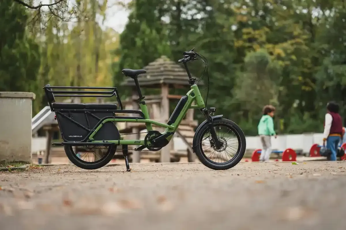 Bicicleta eléctrica LOADY cargo para dos niños  junto a un parque infantil en Valencia