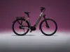 Bicicleta eléctrica negra sobre un fondo degradado rosa.