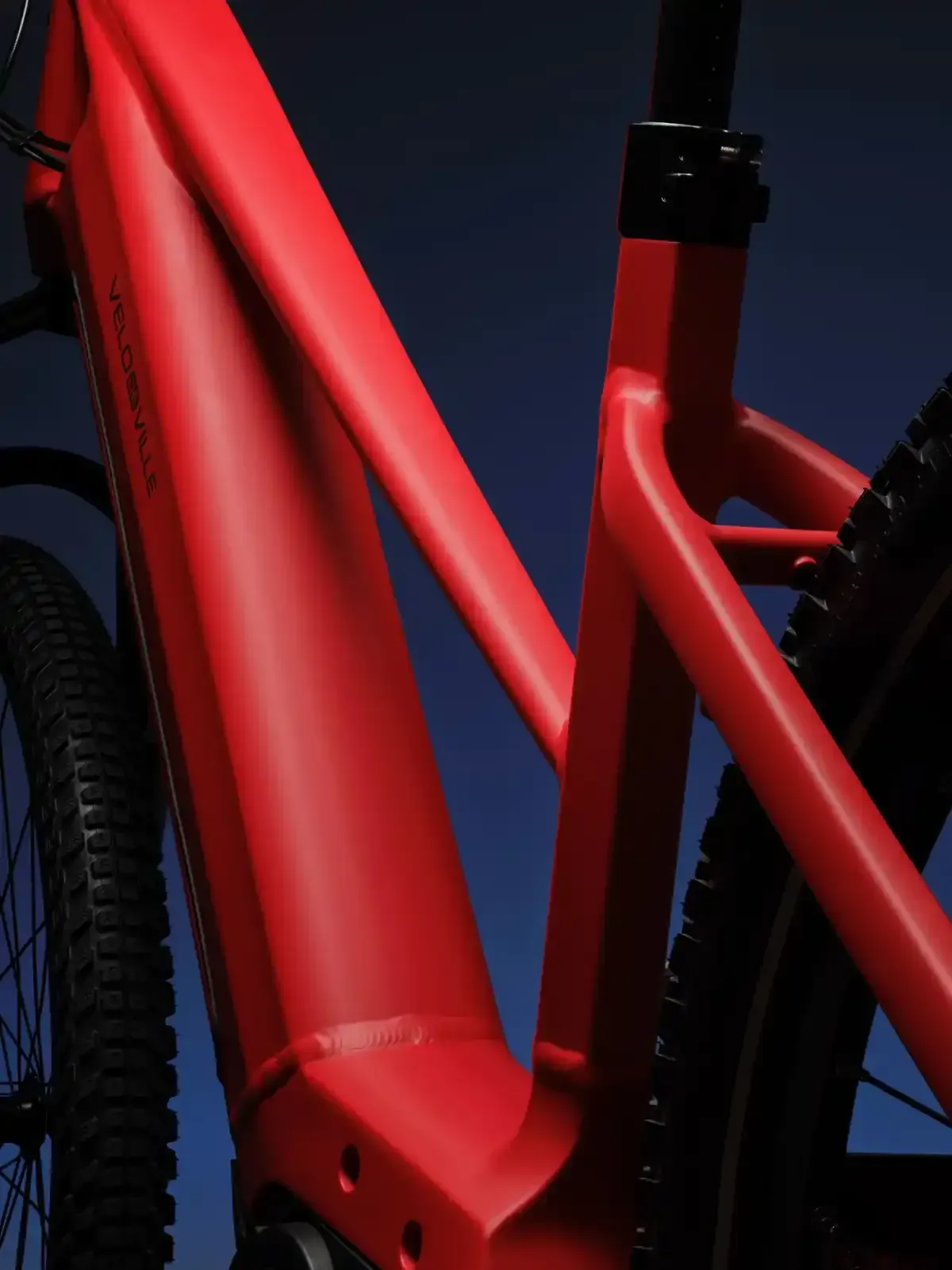 Primer plano de un cuadro de bicicleta rojo y su rueda trasera sobre un fondo oscuro.