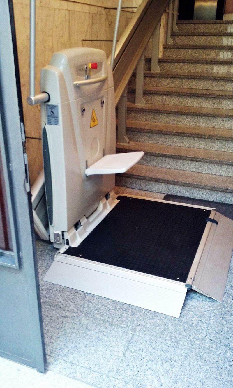 Un elevador de silla de ruedas se encuentra en el suelo al lado de un conjunto de escaleras.