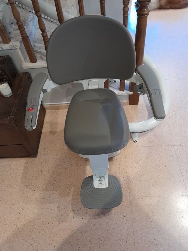 Una silla está colocada sobre un suelo de baldosas al lado de una escalera.