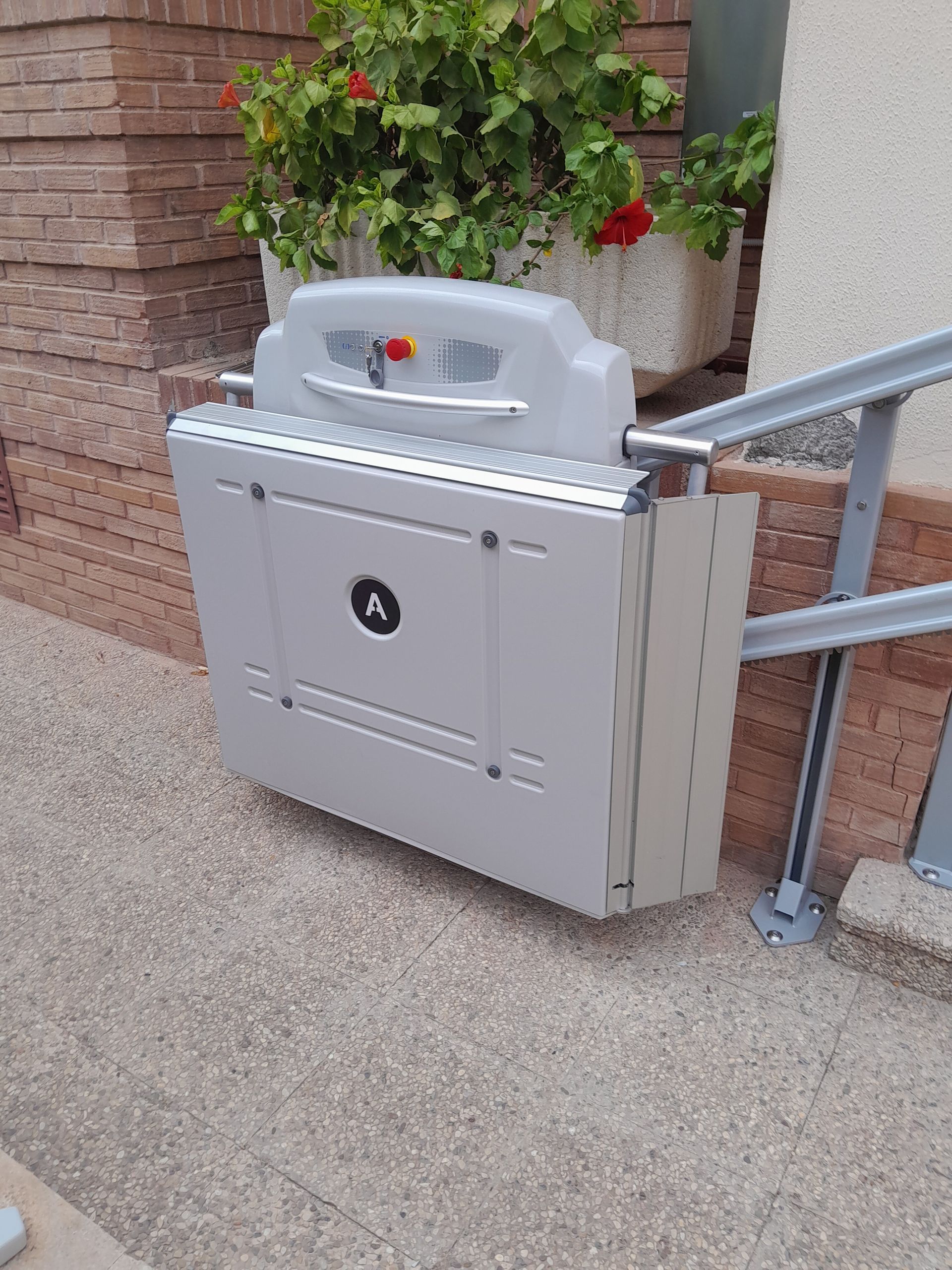 Un salvaescaleras está situado fuera de un edificio, al lado de una pared de ladrillos.