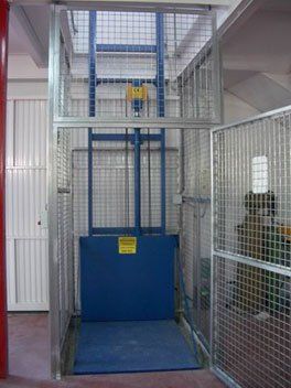 Un ascensor azul está dentro de una jaula en una habitación.