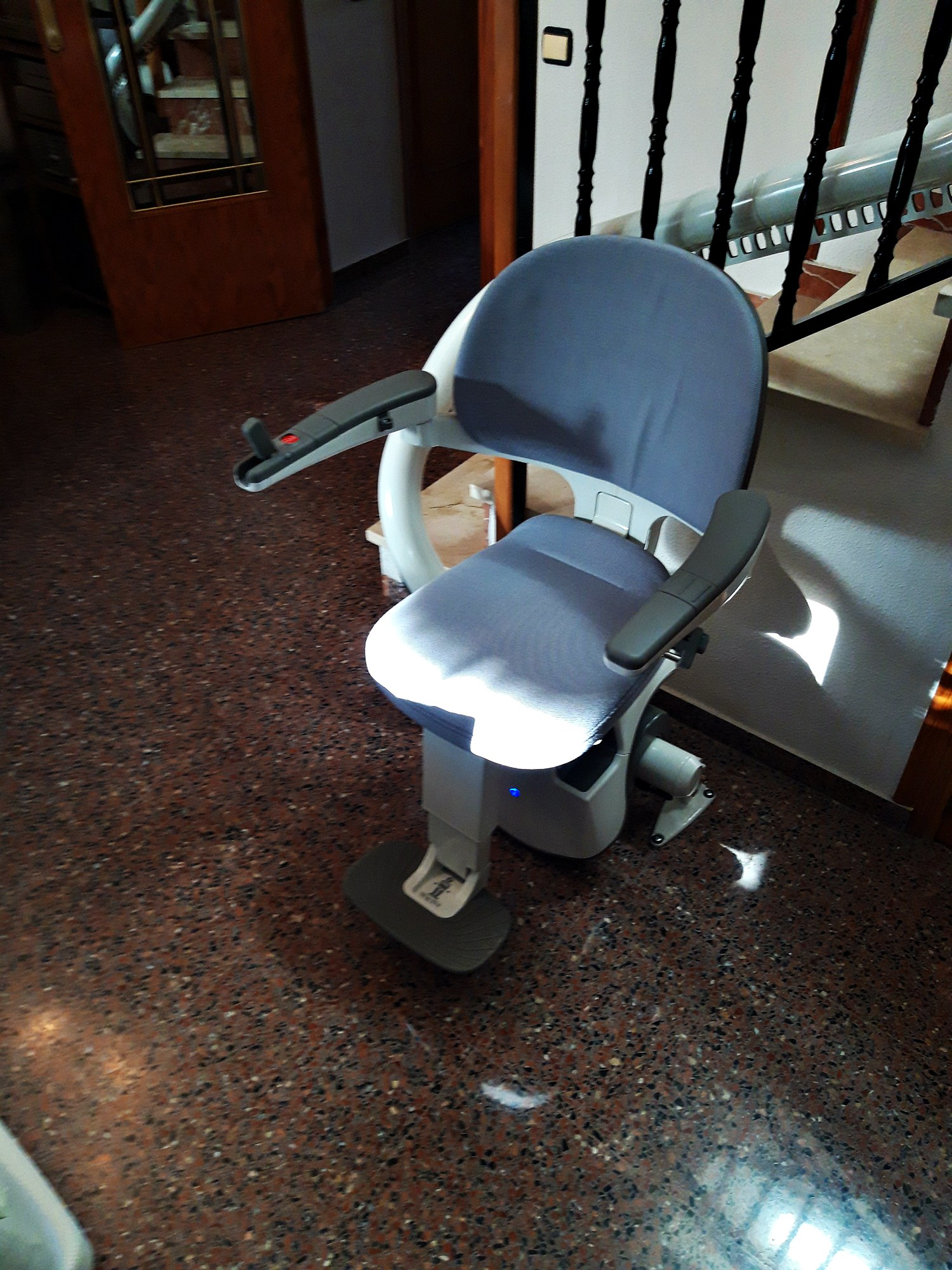 Una silla está colocada sobre un suelo de baldosas al lado de una escalera.