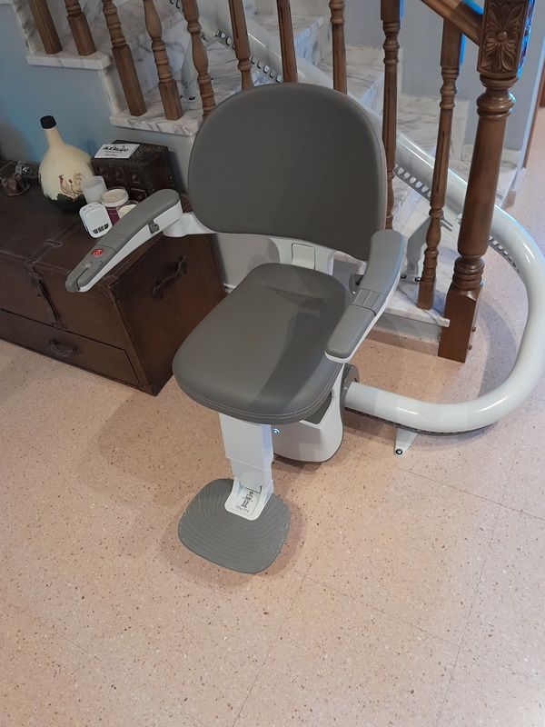 Una silla está colocada sobre un suelo de baldosas al lado de una escalera.