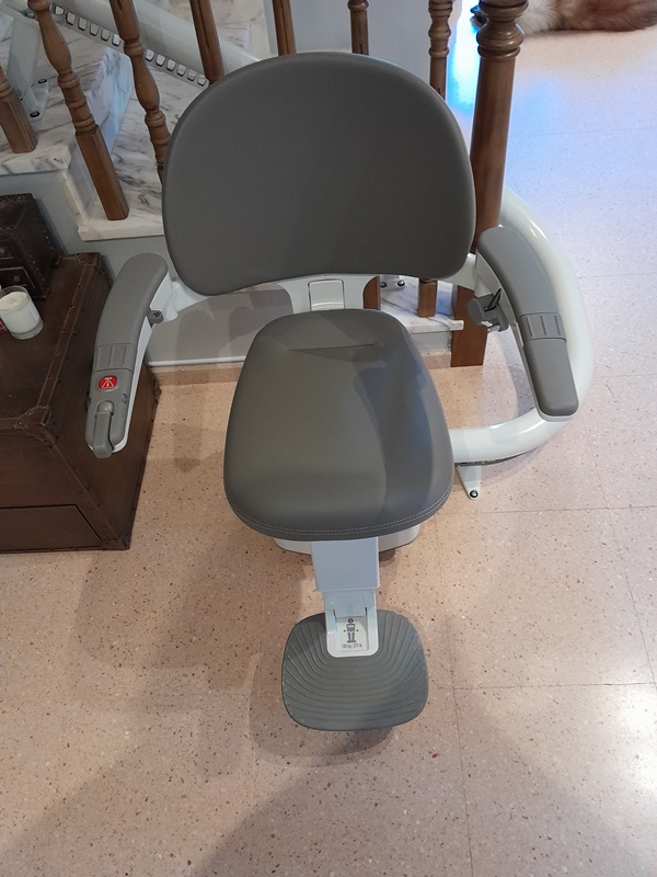 Una silla está colocada sobre un suelo de baldosas al lado de una escalera.