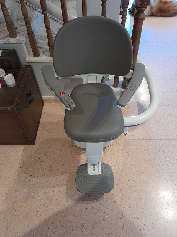 Una silla está colocada sobre un suelo de baldosas al lado de una escalera.