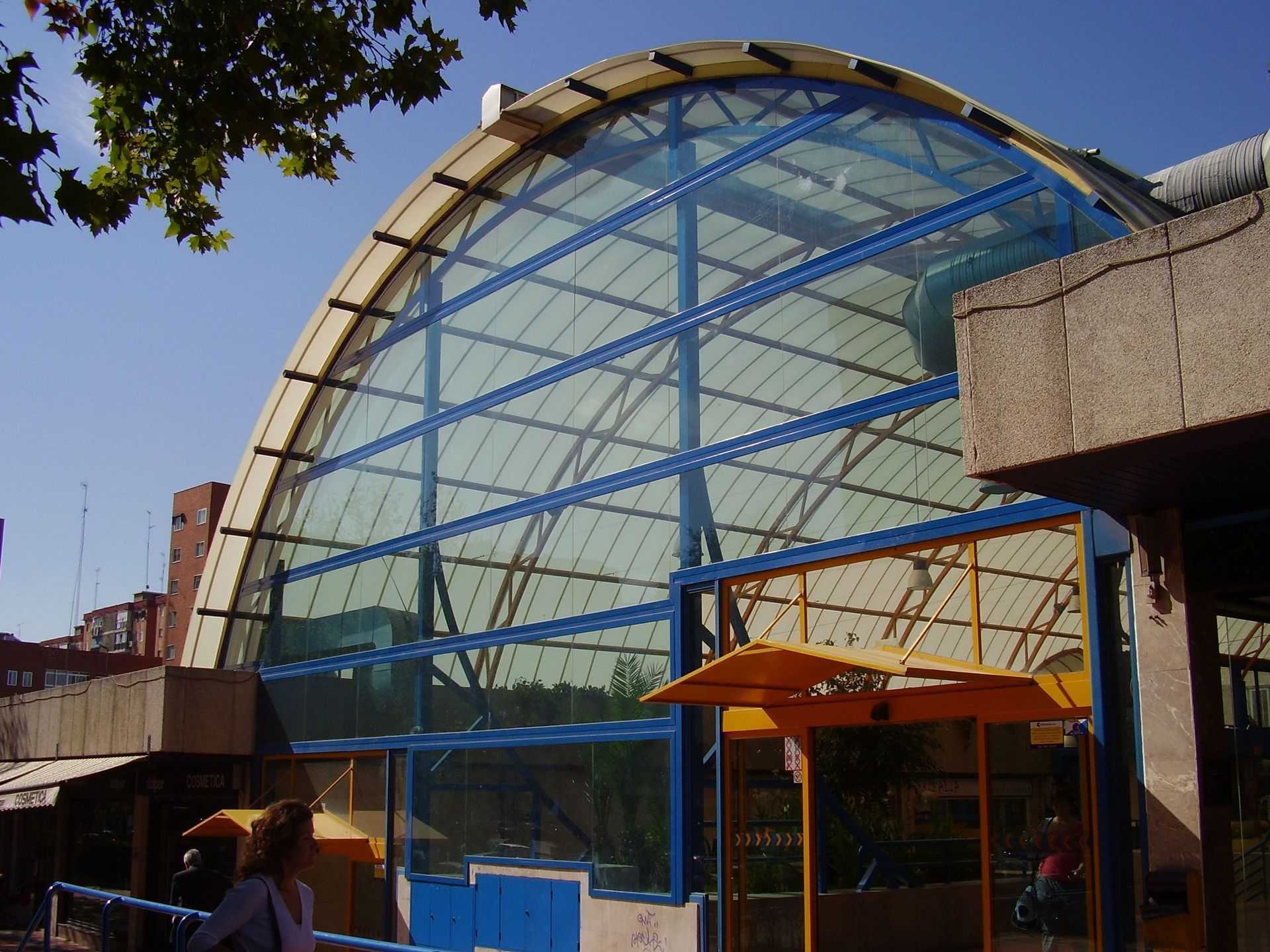 Un edificio con un gran techo de cristal y un toldo amarillo.