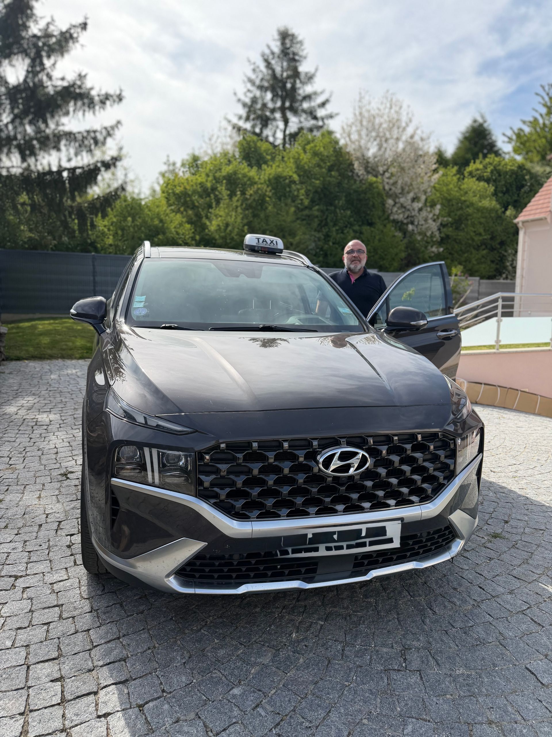 Un SUV Hyundai noir est stationné dans une allée, une personne se tenant près de la portière conducteur ouverte.
