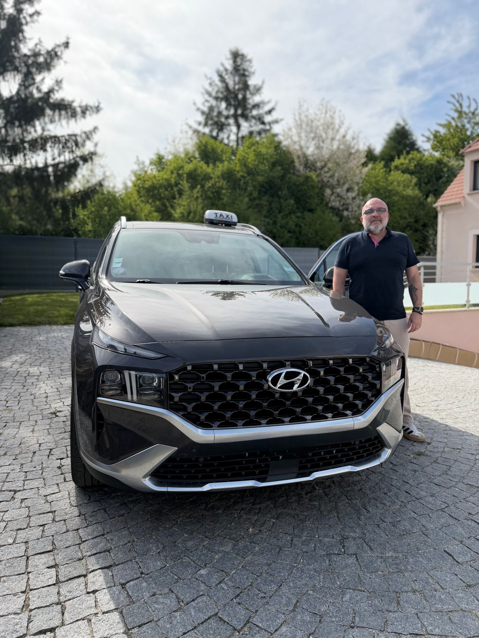 Un SUV Hyundai noir est garé dans une allée, un homme se tenant à côté, à l'extérieur.
