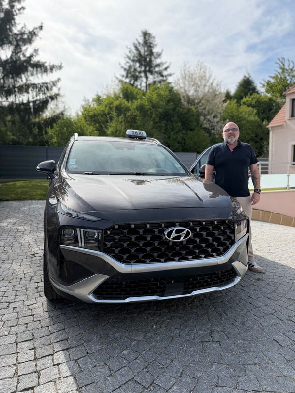 Un SUV Hyundai noir est garé dans une allée, un homme se tenant à côté, à l'extérieur.