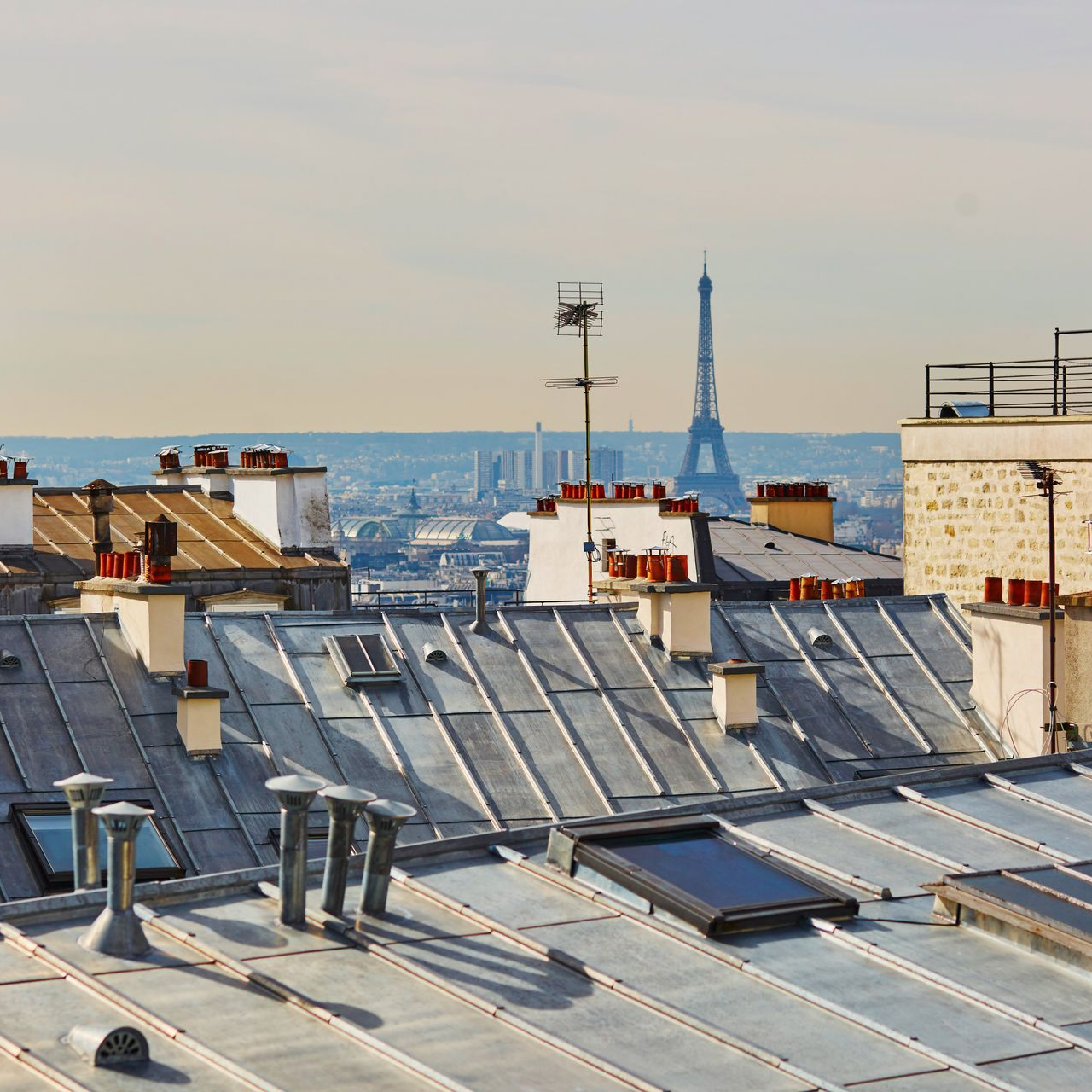 Toits de Paris avec la Tour Eiffel au loin sous un ciel brumeux