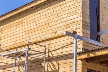 Échafaudage à côté d'un bâtiment en bois en construction, sous un soleil éclatant