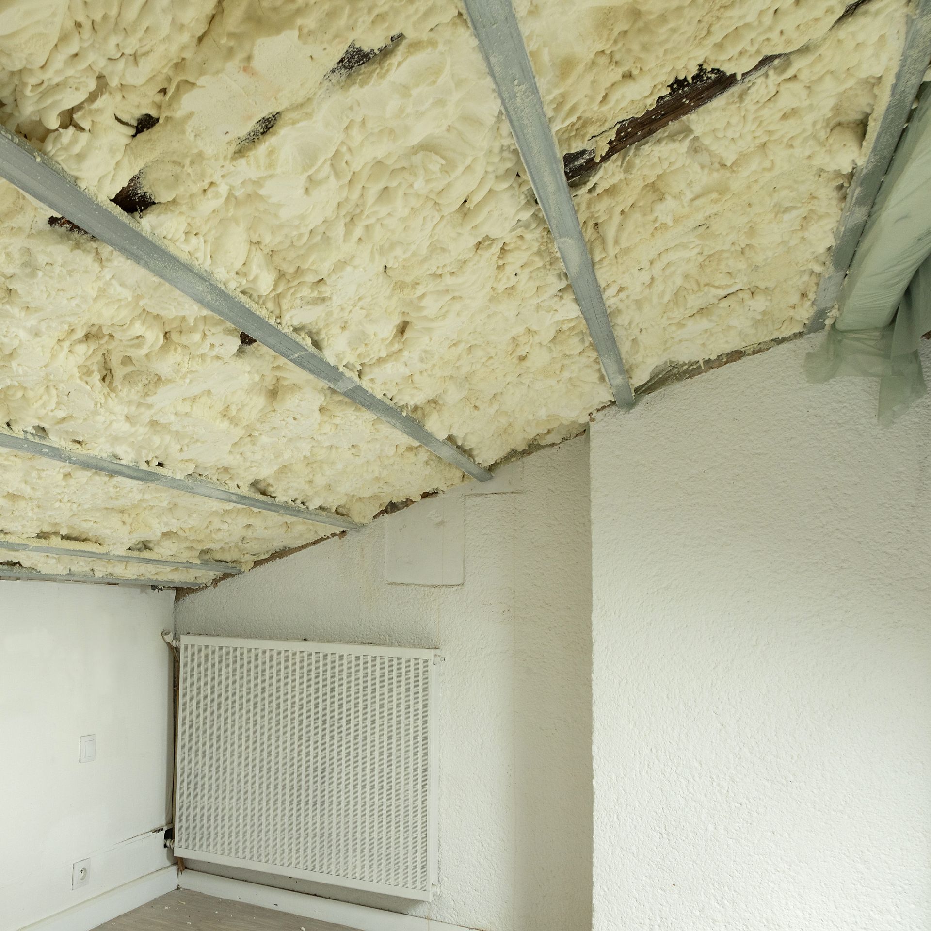 Plafond intérieur en construction avec isolation apparente et ossature métallique au-dessus d'un radiateur