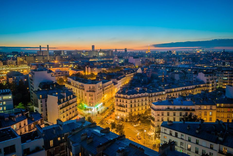 Paysage urbain au crépuscule, avec des rues illuminées et des bâtiments historiques.