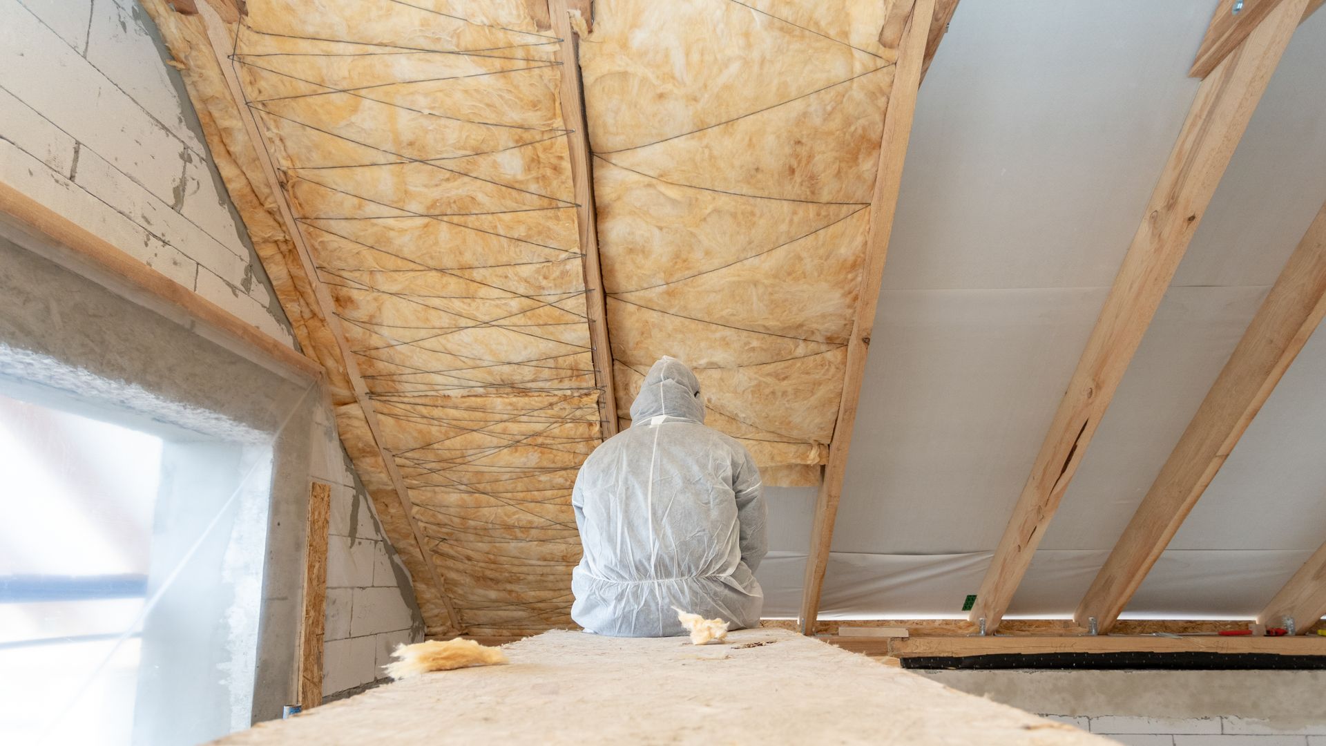 Statue sous un plafond de grenier inachevé, avec isolation apparente et poutres en bois