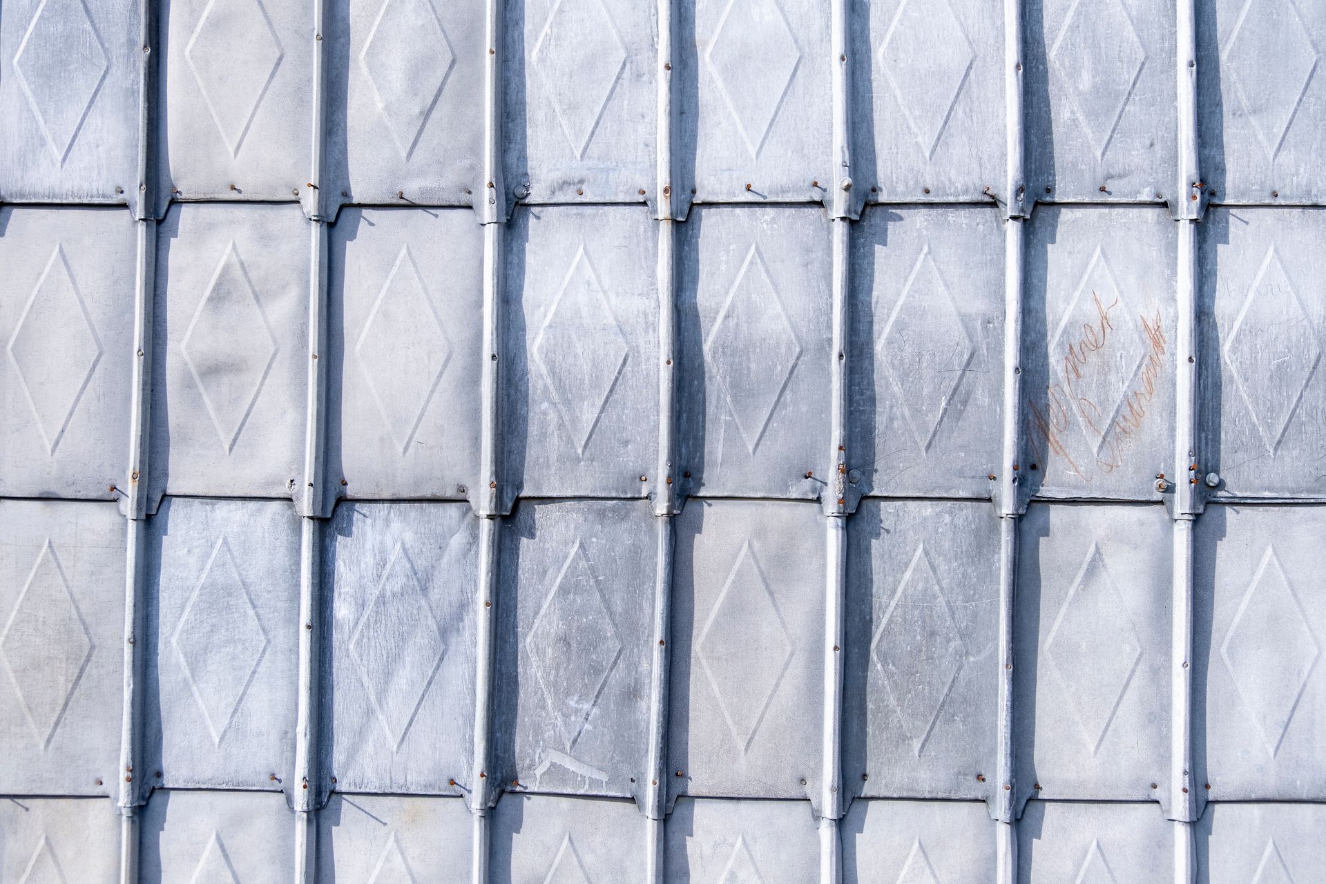 Façade en métal gris avec panneaux verticaux répétitifs et textures en forme de losange