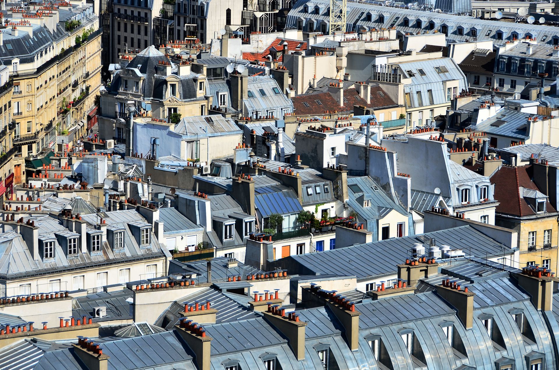 Toits denses d'une ville aux bâtiments blancs et gris sous la lumière vive du jour
