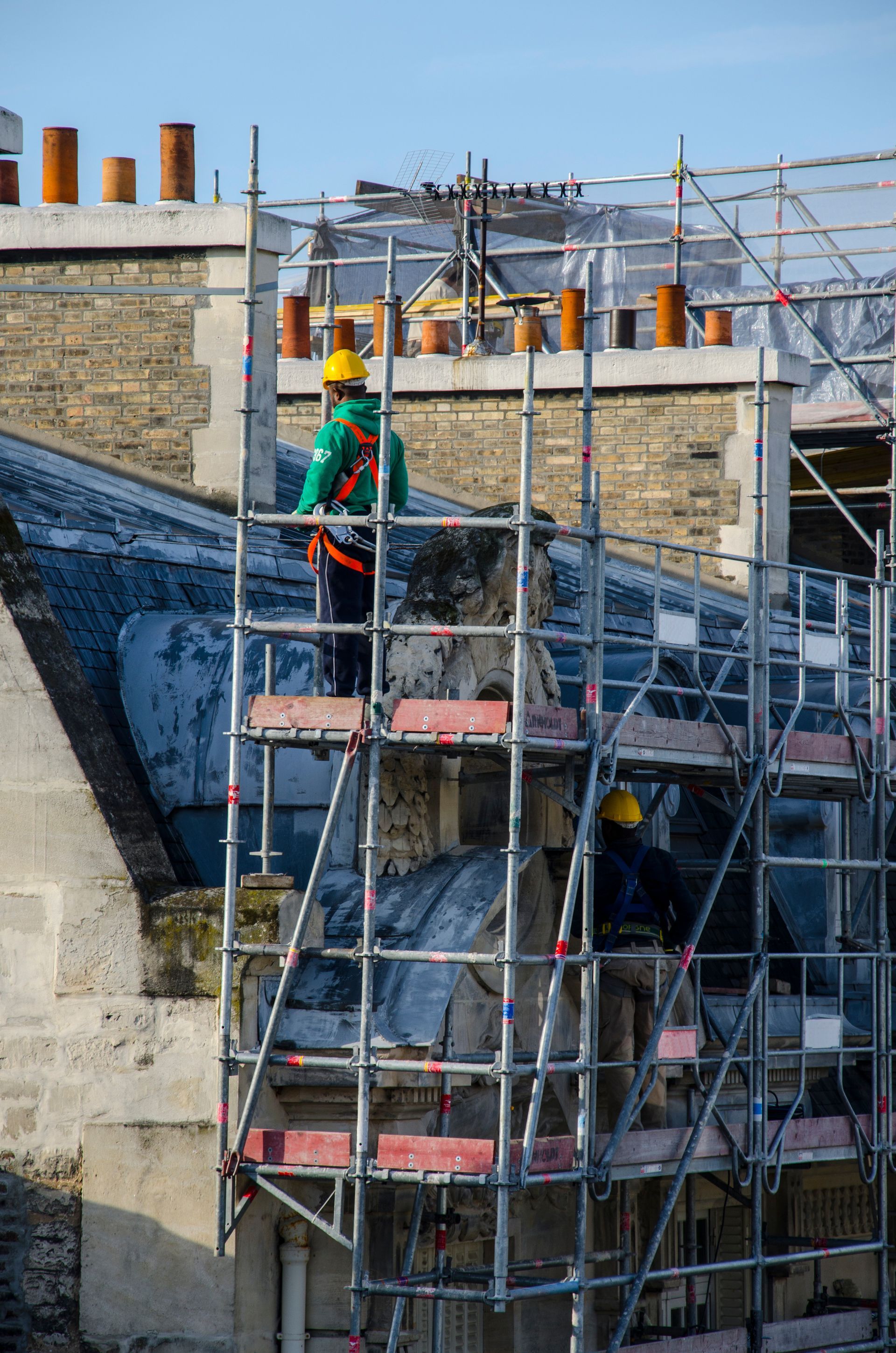 Ouvrier en tenue de sécurité sur un échafaudage sur un chantier de construction.