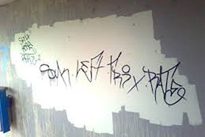 Eine weiße Wand mit schwarzen Graffiti darauf.