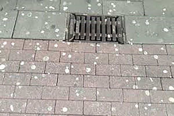 Ein Abfluss auf einem Gehweg mit vielen weißen Flecken darauf.