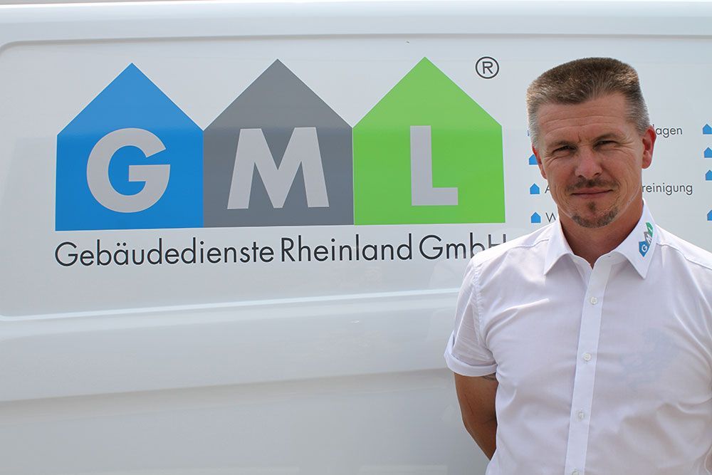 Ein Mann in einem weißen Hemd steht vor einem Lieferwagen mit der Aufschrift „gml“