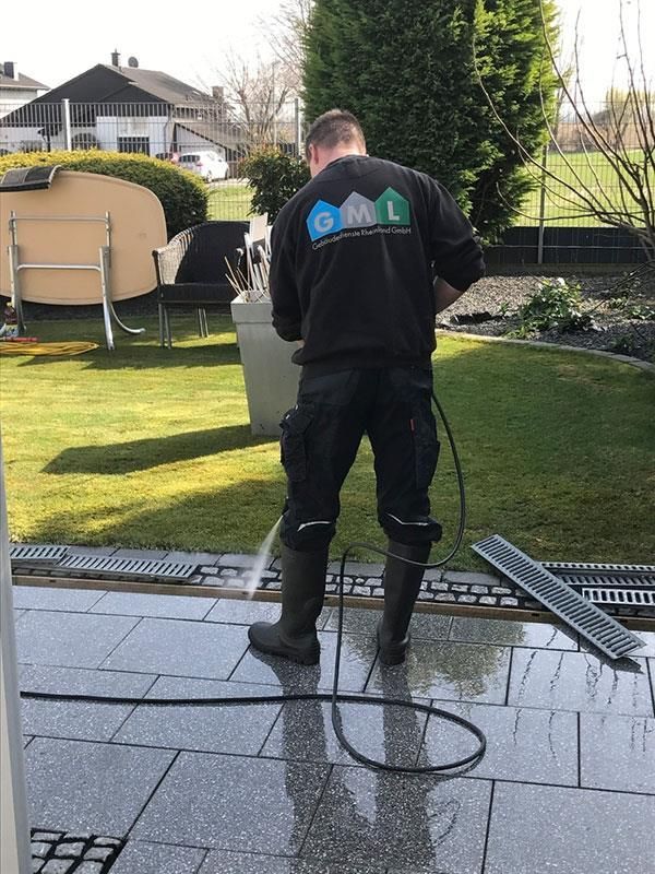 Ein Mann reinigt eine Terrasse mit einem Hochdruckreiniger