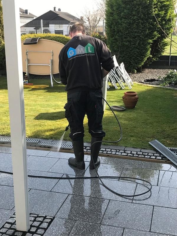 Ein Mann reinigt eine Terrasse mit einem Hochdruckreiniger