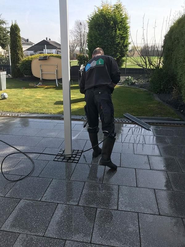 Ein Mann reinigt eine Terrasse mit einem Hochdruckreiniger.