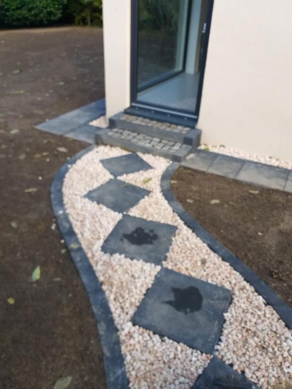 Ein Gehweg mit Kies und Trittsteinen vor einem Haus