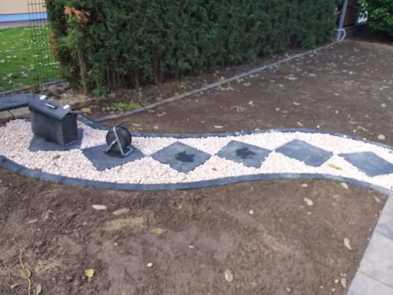 Ein Rasen mit einer Einfassung aus Kies und Steinen.