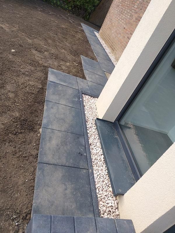 Eine Treppe mit Kies zwischen den Stufen und einem Fenster.