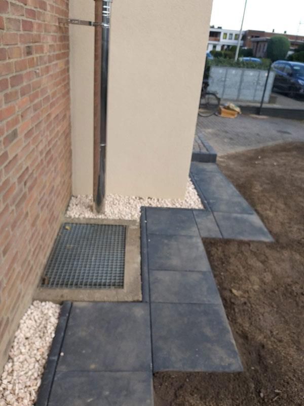 Ein Bürgersteig mit einem Abfluss und einer Ziegelmauer im Hintergrund