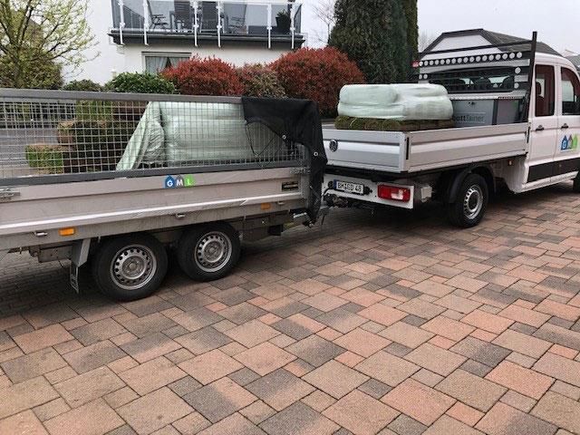 Auf einer gepflasterten Auffahrt parkt ein Lastwagen mit Anhänger.