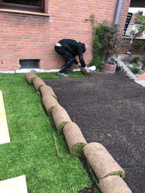 Ein Mann arbeitet auf einem Rasen vor einem Backsteingebäude.