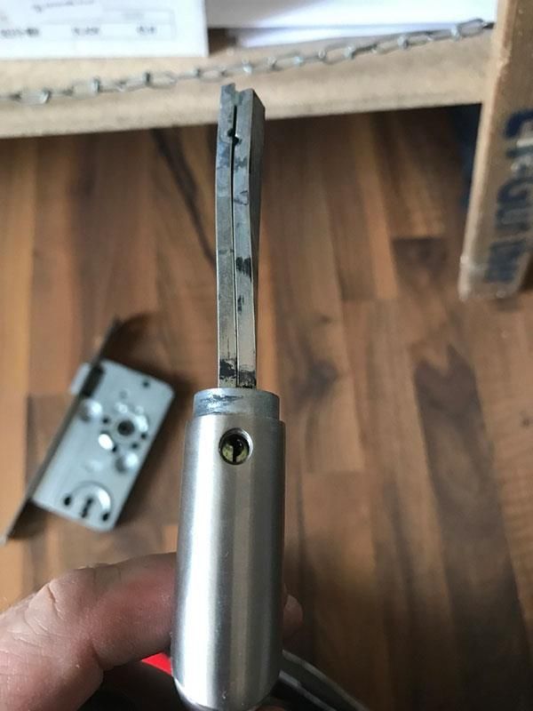 Eine Person hält einen Metallgegenstand auf einem Holzboden in der Hand.