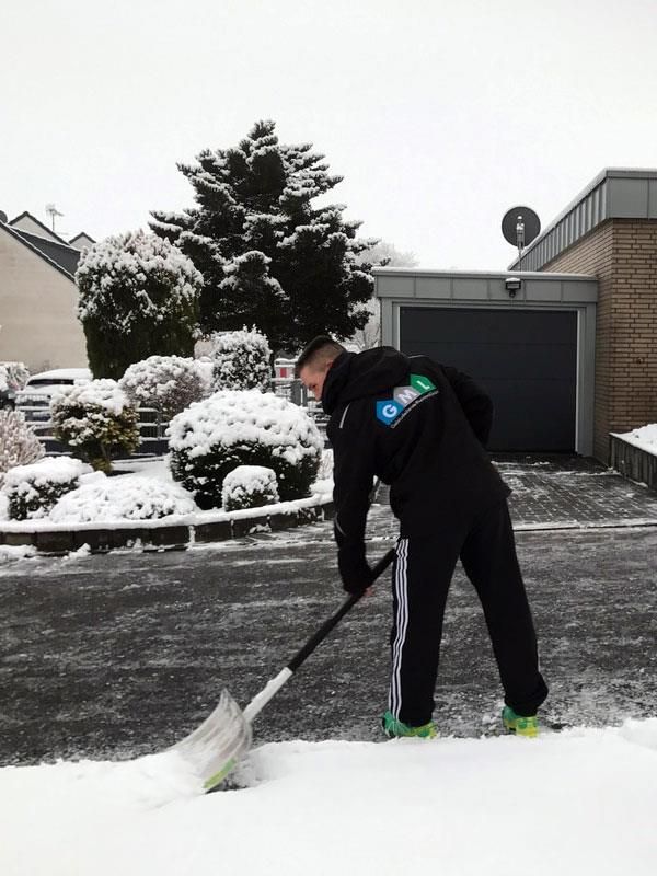 Ein Mann schaufelt Schnee vor einem Haus
