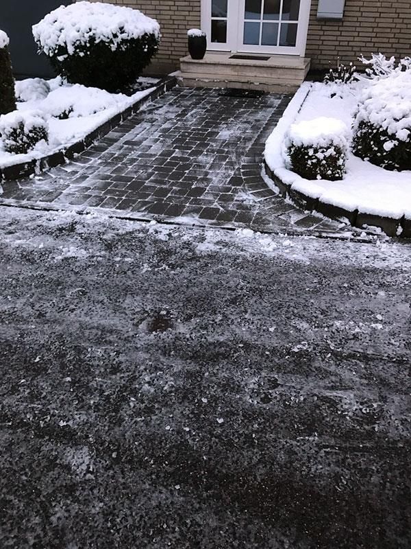 Eine verschneite Auffahrt vor einem Backsteinhaus
