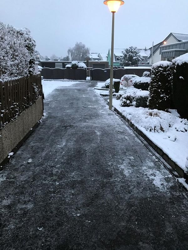 Eine verschneite Auffahrt mit einer Straßenlaterne in der Mitte