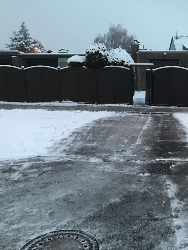 Eine verschneite Auffahrt mit einem Zaun im Hintergrund