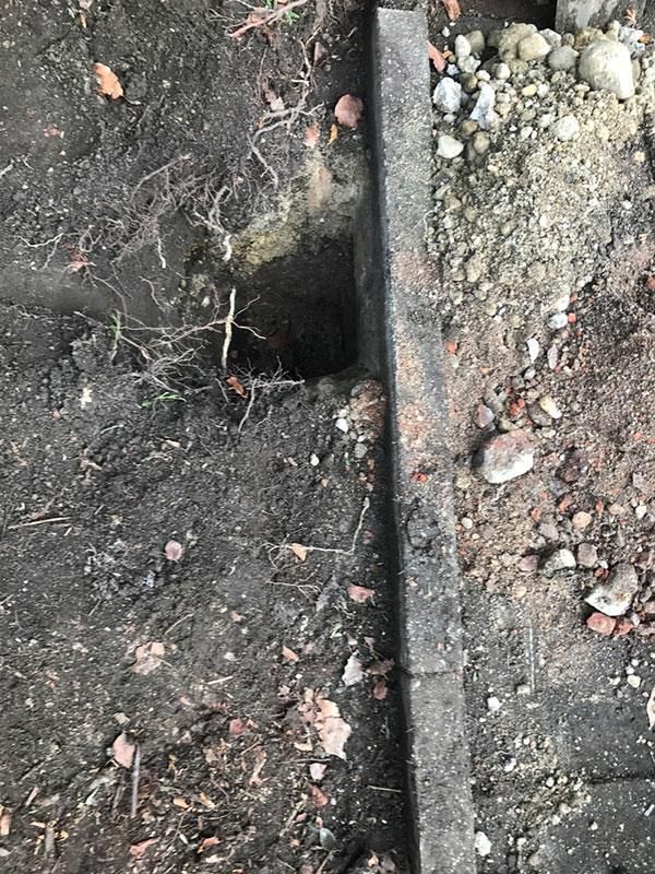 Eine Nahaufnahme eines Lochs im Boden neben einem Betonbordstein.